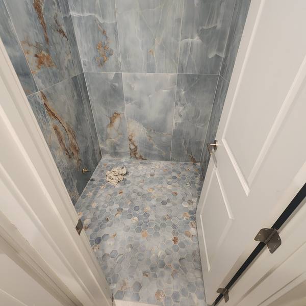 Shower with blue veined wall tile and hex mosaic floor