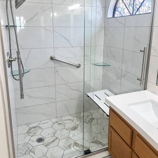 Shower with marble-look wall tile, hex floor, and a glass sliding door