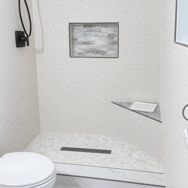 Shower with textured white wall tile, a glass tile niche, and a linear drain