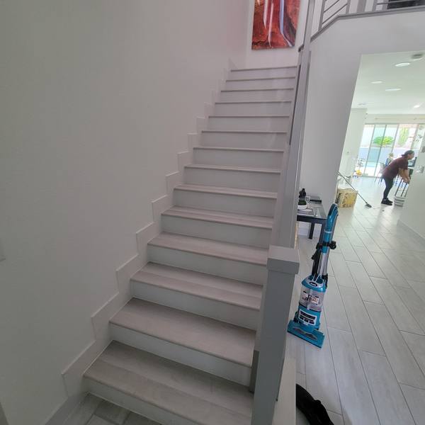 Staircase with light gray treads next to a tile floor