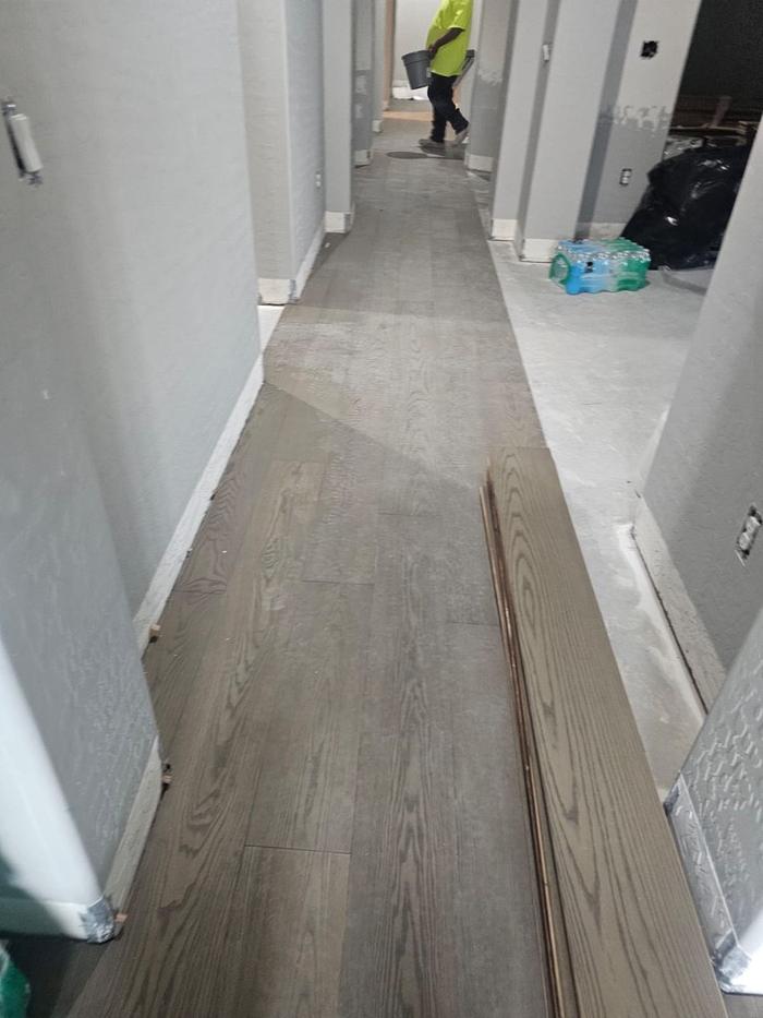 Engineered hardwood planks being glued down in the main hallway