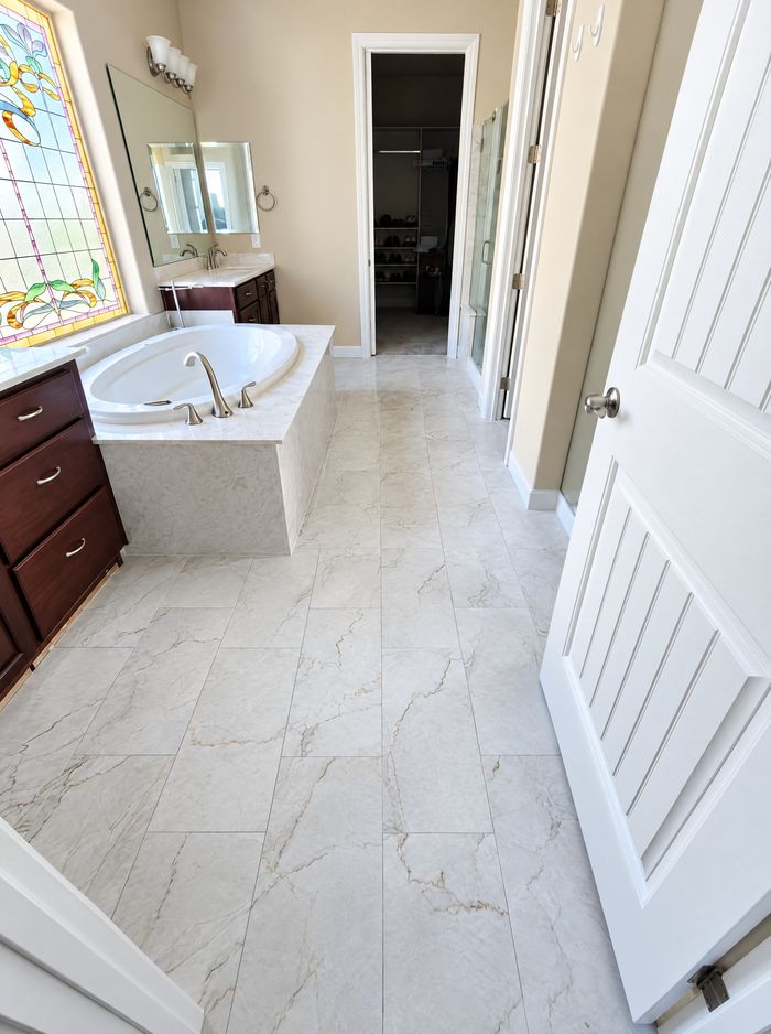 Same primary bath finished in white marble-look tile